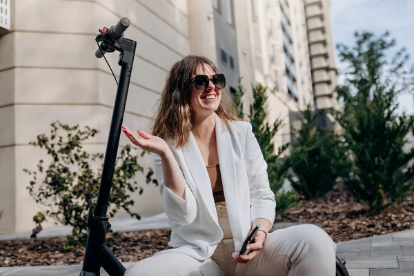 Smiling Businesswoman White Suit Sitting Electric Scooter Waving Friend Walking — Φωτογραφία Αρχείου