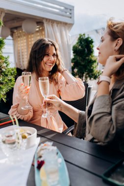 Two Women friends eating fresh oysters and drinking chilled prosecco wine on the summer sunset in restaurant. Seafood delicacies