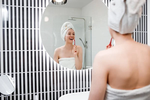 浴室の鏡の前に白いタオルで歯を磨く美しい若い女性の肖像画 朝のルーチンの美しさ手順 — ストック写真