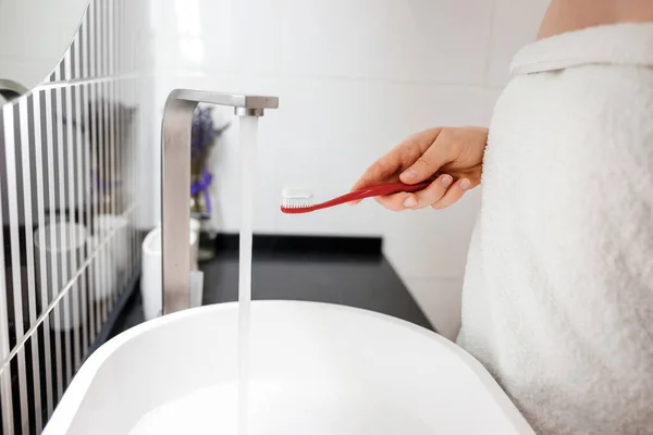 バスルームに立ちながら歯磨き粉で女性の手を保持歯ブラシの閉じる — ストック写真