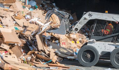 Victoria, British Columbia / Kanada - 30 / 04 / 2019: Bir vaşak operatörü ticari bir geri dönüşüm tesisinde işlenmek üzere karton yığınları yığıyor.