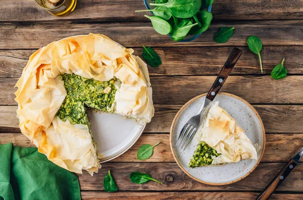 Vegetarian spinach pie with feta cheese on wooden background. Traditional Greek spinach pie Spanakopita