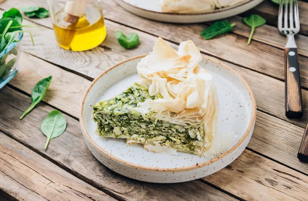 Vegetarian spinach pie with feta cheese on white wooden background. Traditional Greek spinach pie Spanakopita