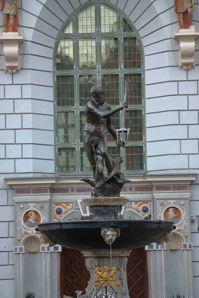 格但斯克 17世纪上半叶 一个带有海王星雕像的洛可可喷泉 其背景是15世纪的哥特式阿得斯宫 以前是商人聚会的地方 是社会生活的中心 — 图库照片