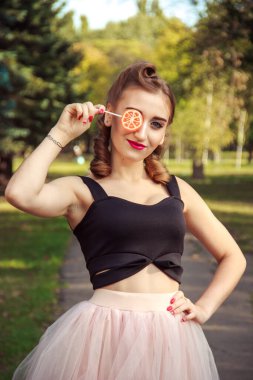 portrait of cheerful girl in pin-up style with lollipop