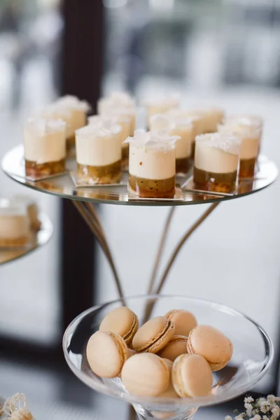 Bright desserts in cups on the wedding table and macaroons