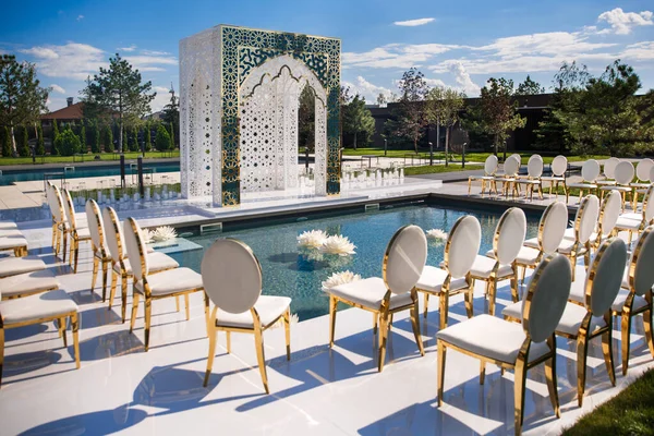 Outdoor wedding ceremony in the garden near the pool.