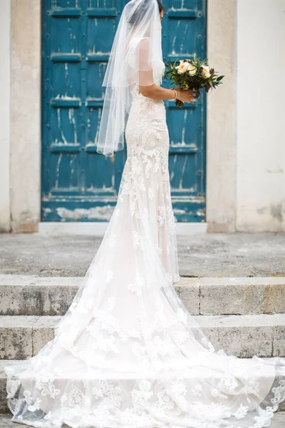 Taş basamaklarda çiçeklerle genç bir gelin.