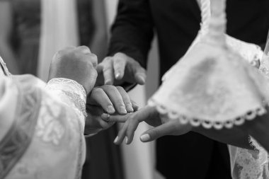 The priest in the church puts rings on the bride and groom.