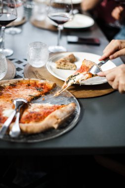 Adam şenlik masasından bir dilim pizza kesiyor..