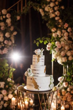 Düğün pastası tören alanında çiçeklerle süslenmiş..