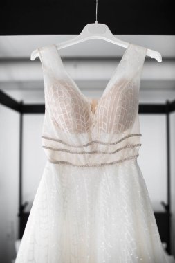 Gelinlik otel odasındaki yatağın üstünde asılı.