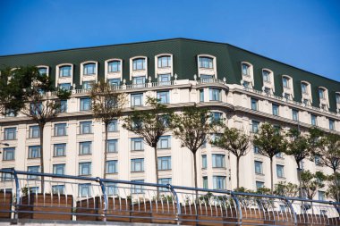 Şehirde büyük bir otel ve sıra sıra ağaç var..