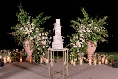 Düğün pastası tören alanında çiçeklerle süslenmiş..