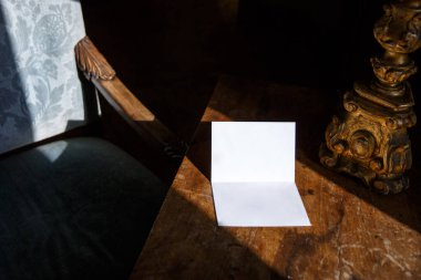 Eski ahşap masanın üzerinde boş bir kağıt parçası.