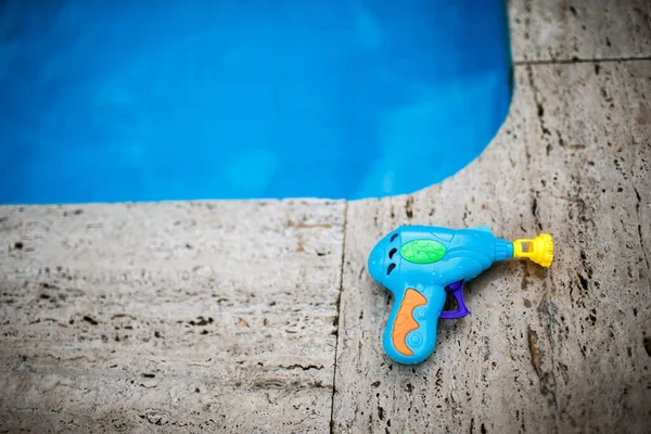 Plastic bubble gun at the edge of the pool.