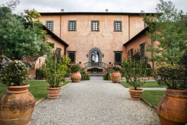 Ağaçlar ve çiçeklerle dolu büyük saksıları olan bir villa..