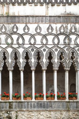 Çiçek saksılarındaki kapalı bitkiler taş sütunların arasında duruyor..