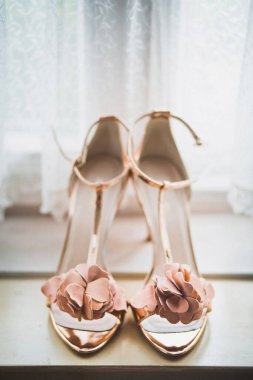Ahşap pencere eşiğinde pembe düğün ayakkabıları..
