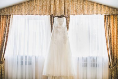 Gelinlik pencerenin yanındaki odada asılı..