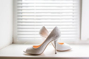 Plastik pencere pervazında beyaz düğün ayakkabıları..