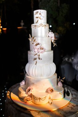 Pembe çiçeklerle süslenmiş çok katlı düğün pastası..