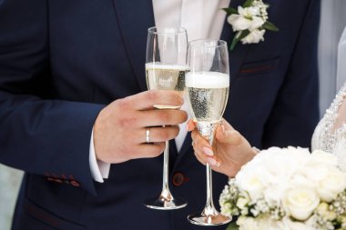 Yeni evlilerin ellerinde şampanya için iki düğün kadehi..