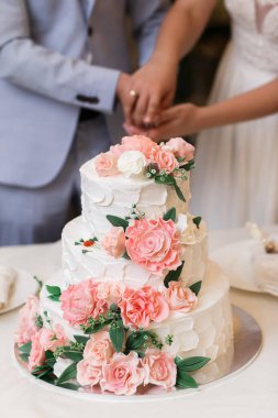 Pembe çiçeklerle süslenmiş çok katlı düğün pastası..