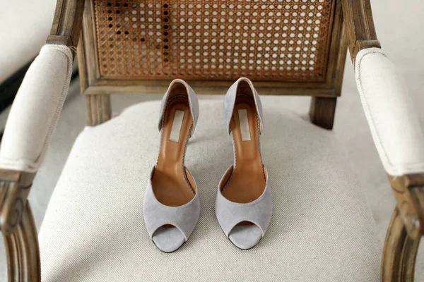 Silver wedding shoes on a beige chair.