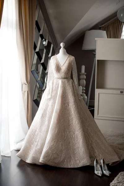 Wedding dress on a mannequin and shoes near the window