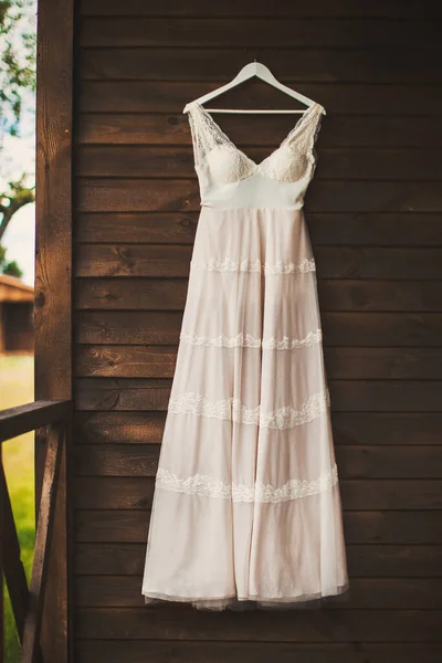 Wedding dress hanging on a wooden wall.