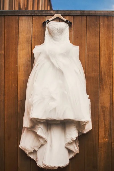 Wedding dress hanging on a wooden wall.