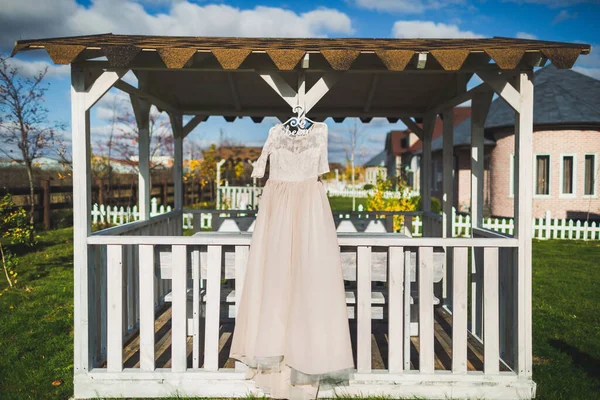 Wedding dress hanging on a wooden arbor.