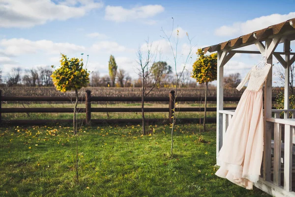 Wedding dress hanging on a wooden arbor.