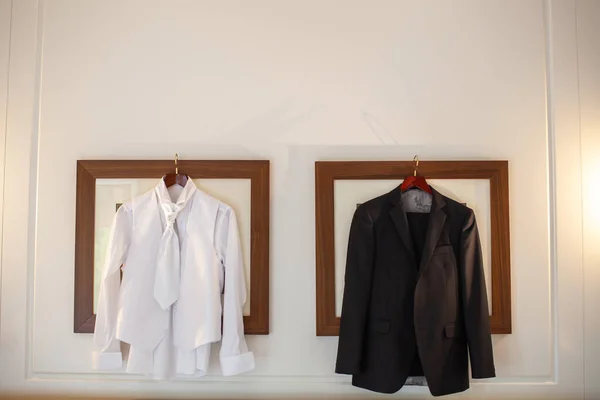Wedding suit and shirt hanging in pictures.
