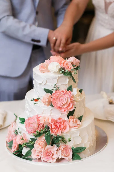 Multilevel wedding cake decorated with pink flowers.