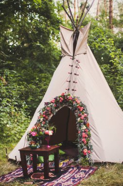 Tepee decorated with flowers for the wedding ceremony.