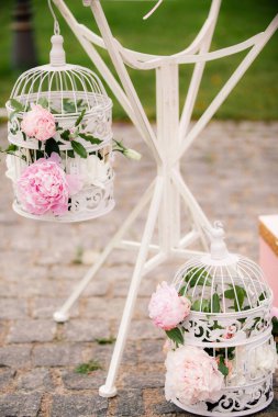 Pink peonies in a cage at a wedding ceremony.