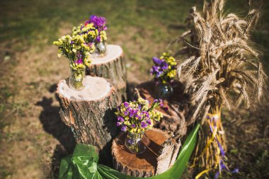 Beautiful and delicate flowers at the wedding ceremony. Flowers in vases on wooden stumps