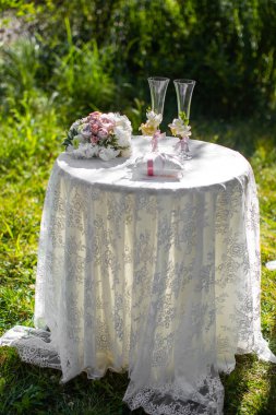 Bright bouquet and wedding glasses on the table.