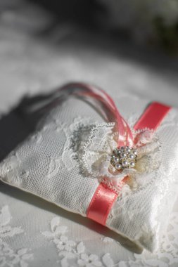 Lace pillow for wedding rings with red ribbon.