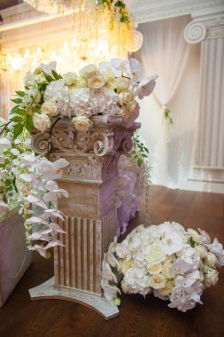 Delicate flowers on a column at a wedding.