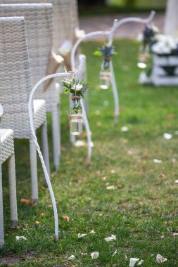 Chairs and bottled flowers nearby at a wedding ceremony.