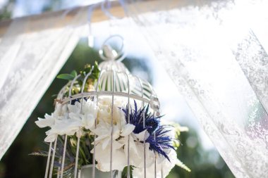 Bright flowers in a metal cage on a wedding arch.