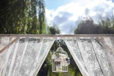 Bright flowers in a metal cage on a wedding arch.