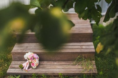 Colorful wedding bouquet lies on wooden steps.