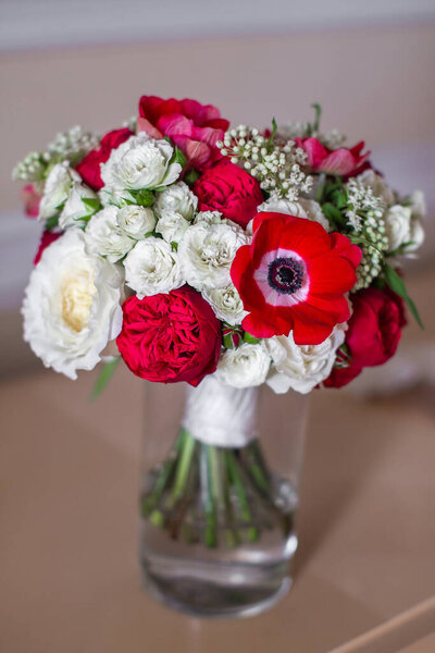 Свадебный букет стоит в вазе с водой.