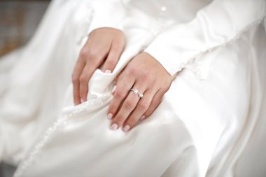 Engagement ring on bride's finger during wedding preparations.