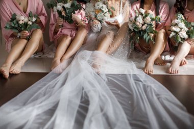 Bride with bridesmaids with flowers sitting in a row.