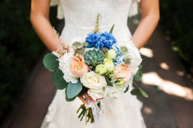 Bright wedding bouquet in hands of the bride.
